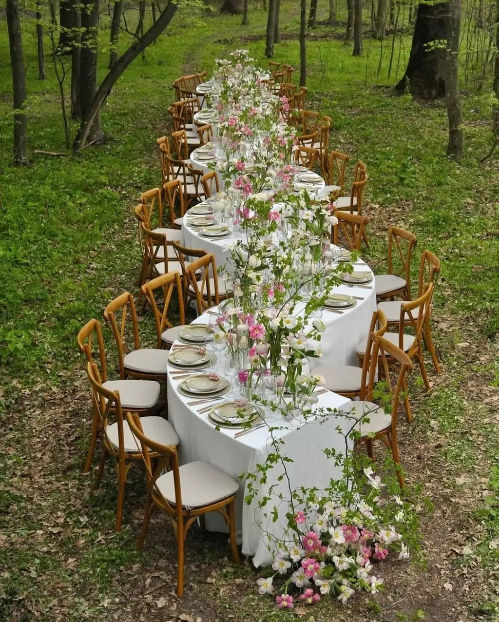 Long banquet table in a forest set with wildflowers