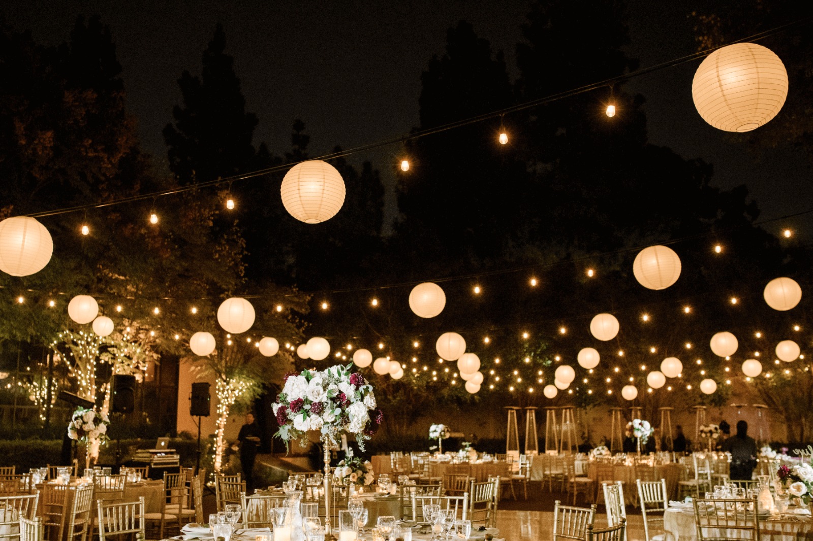 Outdoor evening reception lit by paper lanterns and string lights